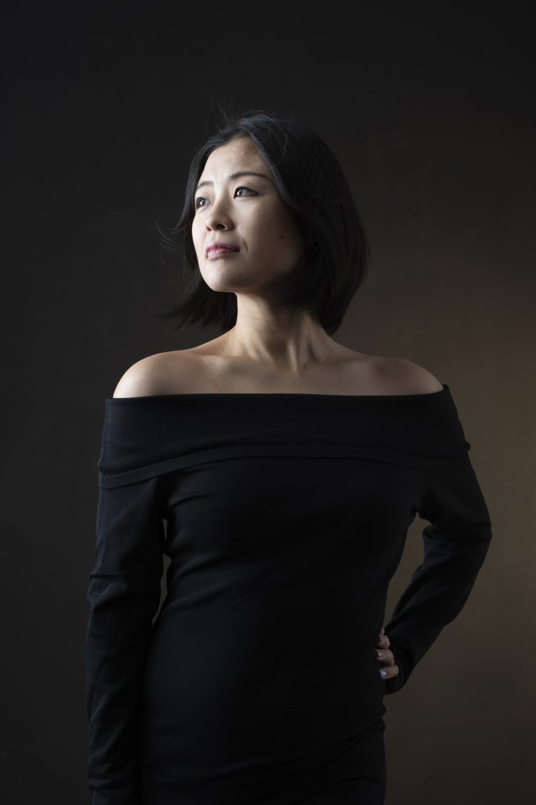 Yong Asian woman in black dress on black background